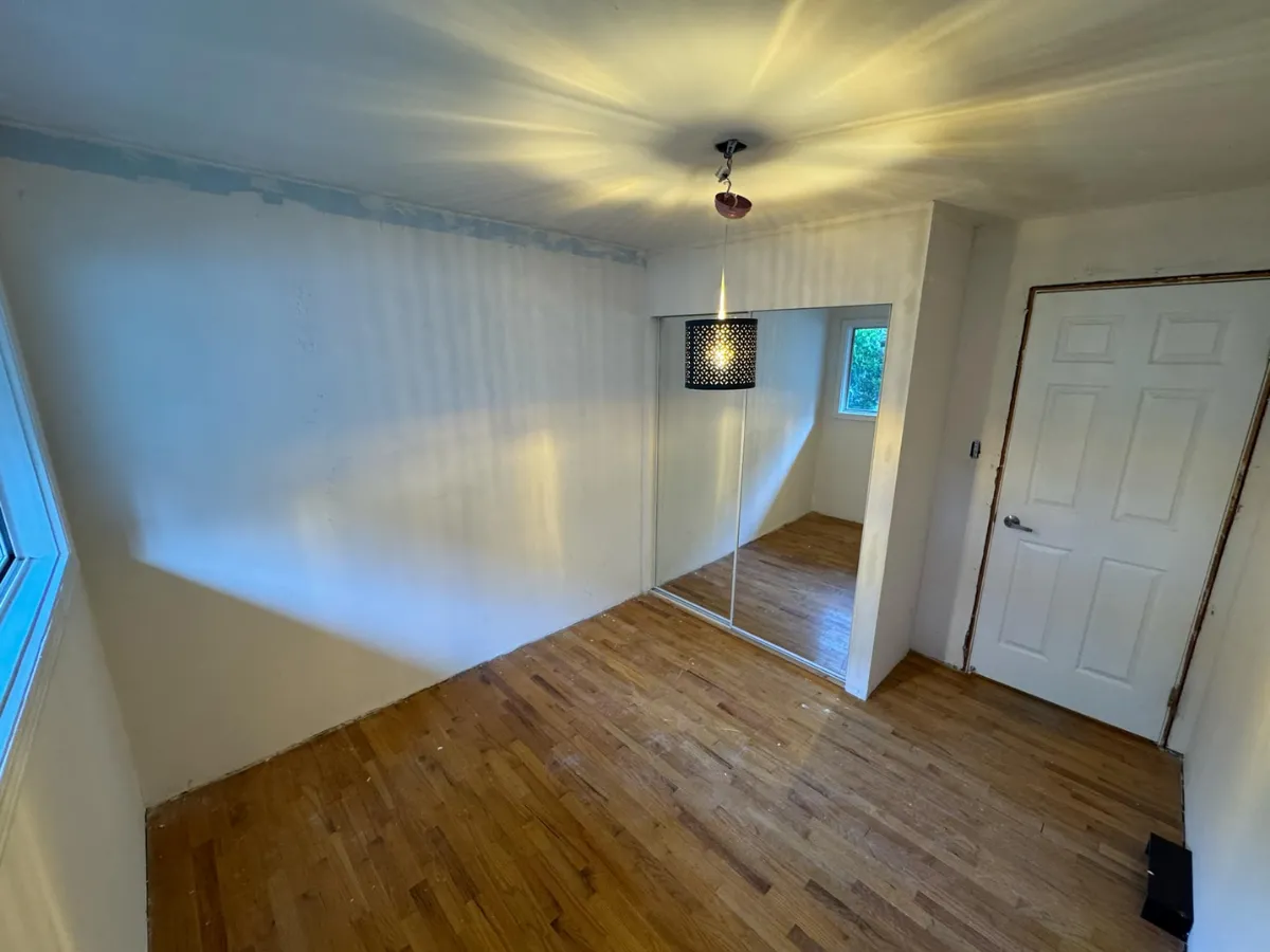 Bedroom before renovation with old flooring and paint